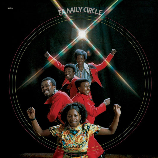 Family Circle band members posing with arms raised in red outfits and colorful dress against dark background