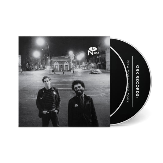 Black and white photo of two men on a city street at night with a CD partially visible titled New York, New York